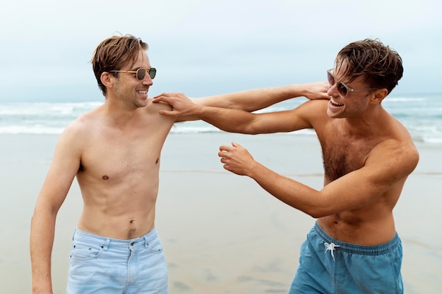 Hombres sonrientes de tiro medio en la playa