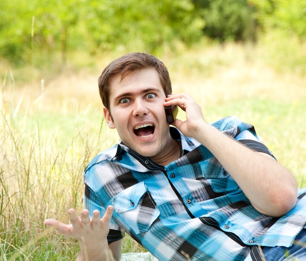 Hombres sorprendidos con teléfono móvil al aire libre.