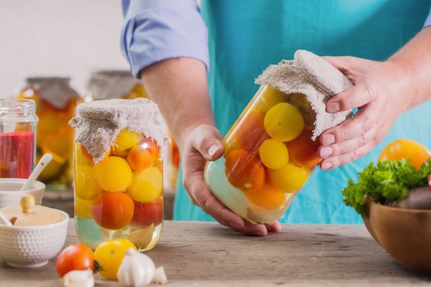 Hombres con tarro de tomates en escabeche