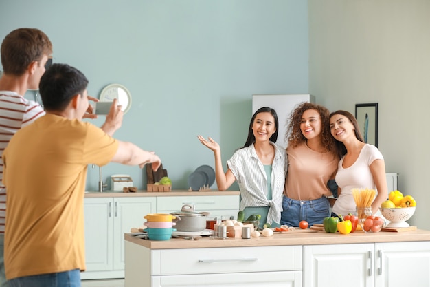 Hombres tomando fotos de sus amigos cocinando en la cocina