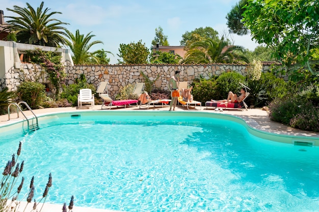 Hombres tomando el sol junto a la piscina