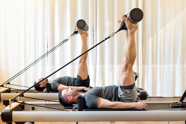 Hombres trabajando en un gimnasio haciendo ejercicios de movilidad de cadera de Pilates