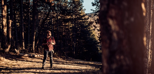 Hombres usando teléfonos inteligentes en bosque de pinos y mirando a distancia