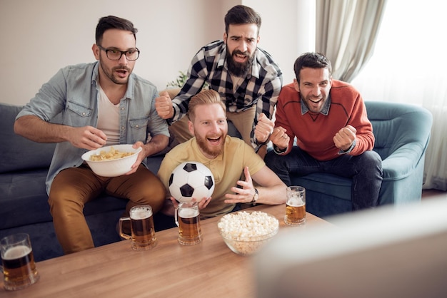 Hombres viendo partidos de fútbol en la televisión