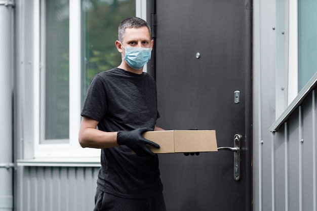 Home Delivery Shopping Box Mann mit Handschuhen und Schutzmaske liefert Pakete an der Tür.