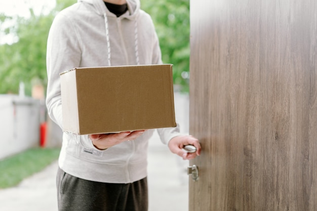 Home Delivery Shopping Box Mann mit Handschuhen und Schutzmaske liefert Pakete an der Tür.