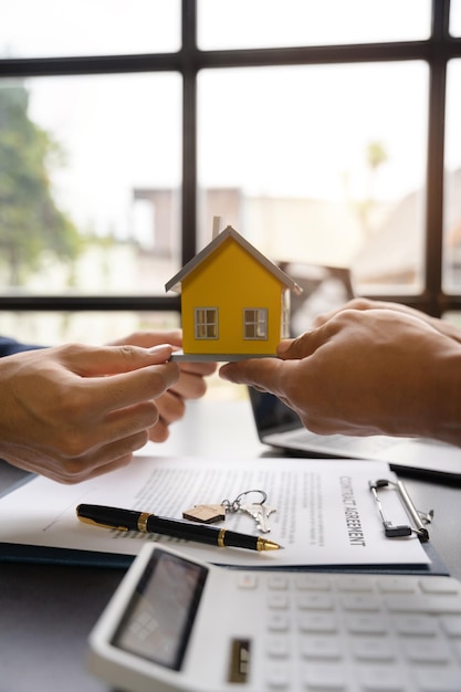 Home Loan Officer sendet Hausmodell an den Kunden nach Unterzeichnung des Vertragsvertrags Immobilien mit genehmigtem Hypothekenantragsformular bezüglich Hypothekendarlehensangebot für und Hausversicherung