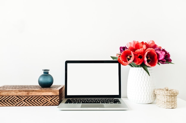 Home-Office-Hintergrund mit Kopie Raum Modell Laptop, Tulpenblumenstrauß, Dekorationen auf weißem Hintergrund