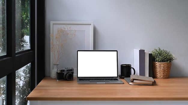 Home-Office-Schreibtisch mit Computer-Laptop-Büchern Zimmerpflanze und Bilderrahmen