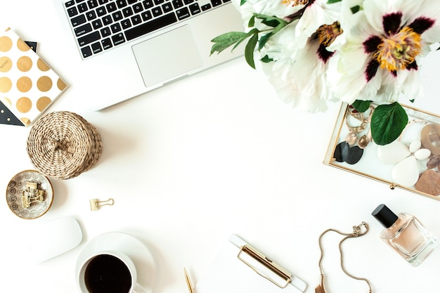 Home-Office-Schreibtisch Tischarbeitsplatz mit Laptop, Blumen und Modeaccessoires auf weißer Oberfläche