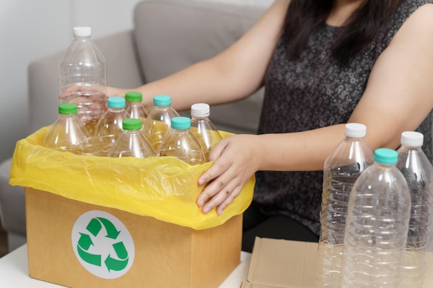 Home recycle eco green zero concept Mujer tirando botella de plástico vacía en el contenedor de reciclaje con bolsas de basura amarillas en casa