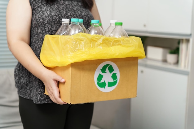 Home Recycle Eco Green Zero Konzept Frau wirft zu Hause leere Plastikflaschen in den Recyclingbehälter mit gelben Müllsäcken