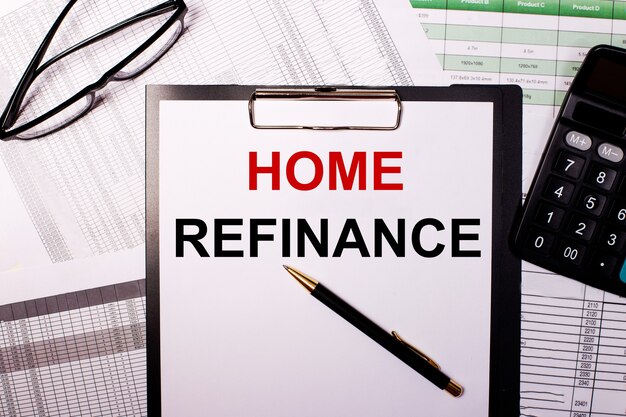 HOME REFINANCE está escrito en una hoja de papel blanca, cerca de los vasos y la calculadora.