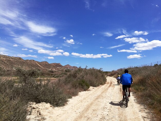 Foto homem a andar de bicicleta na estrada contra o céu