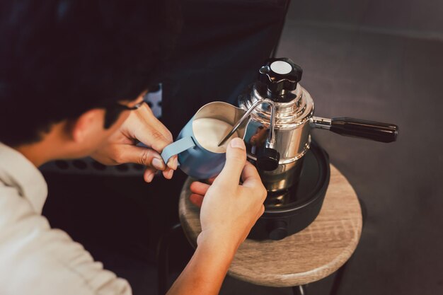 Foto homem a aquecer leite numa jarra de metal com máquina de café a vapor no acampamento ao ar livre