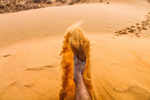 Foto homem a chutar areia na praia