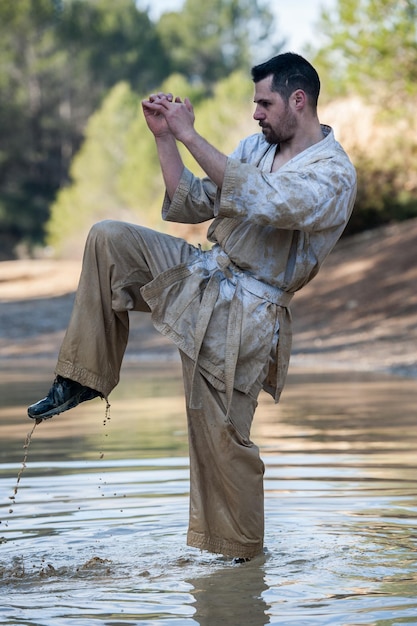 Homem a chutar no lago contra as árvores