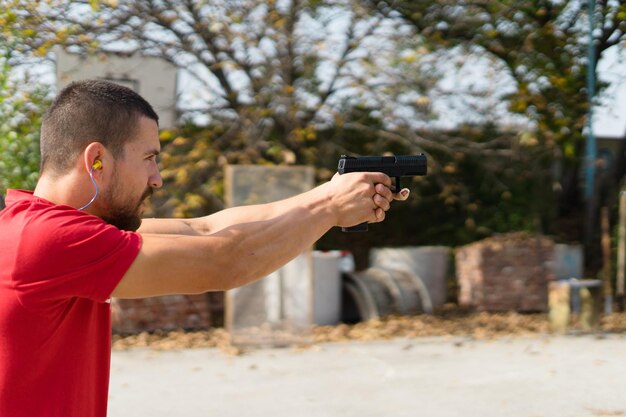 Foto homem a disparar com uma pistola contra árvores