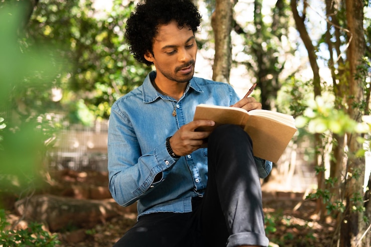 Foto homem a escrever num livro no parque