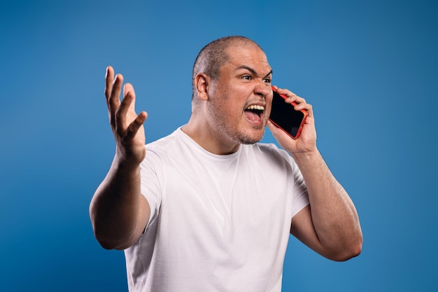 Foto homem a falar ao telemóvel com raiva.