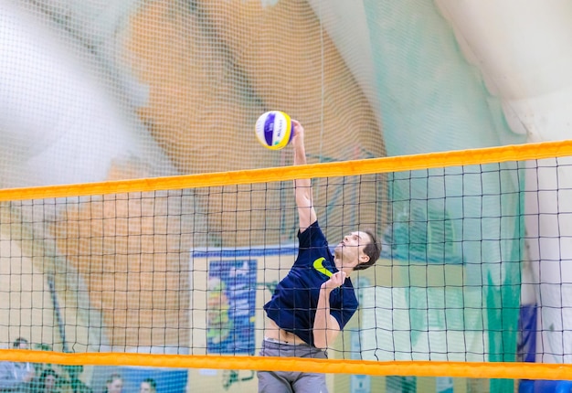 Foto homem a jogar voleibol na areia.