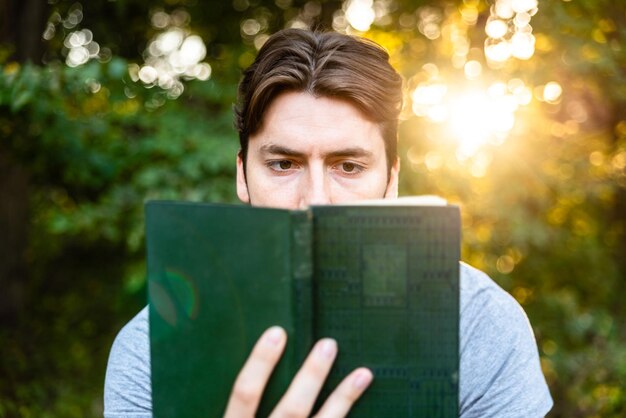 Foto homem a ler um livro contra as árvores