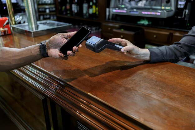 Homem a pagar com o telemóvel num bar.