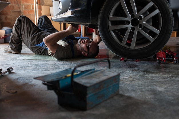 Foto homem a reparar um carro na garagem