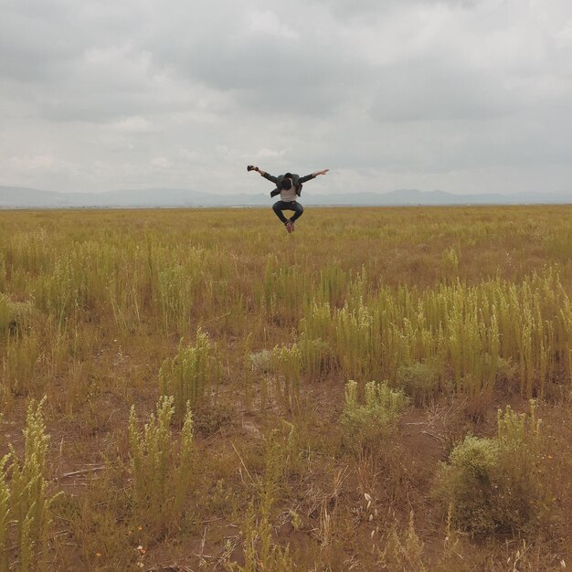 Foto homem a saltar no campo.