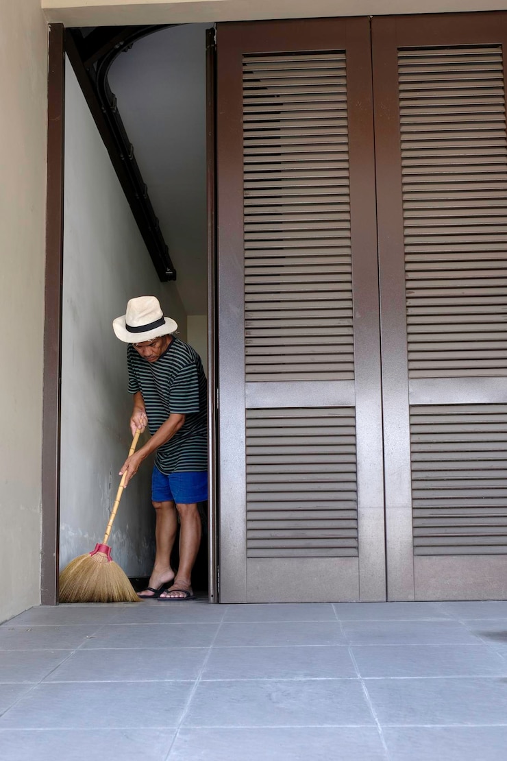 Foto homem a varrer o chão do seu porão