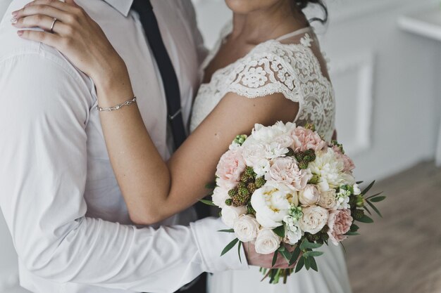 Homem abraça a cintura de uma mulher segurando um buquê de flores 7396