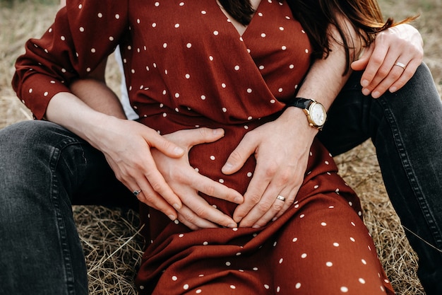 Homem abraçando a barriga da mulher grávida, ao ar livre