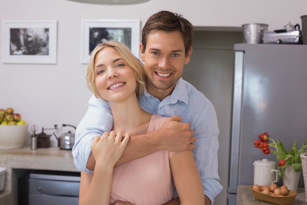 Homem abraçando mulher de trás na cozinha