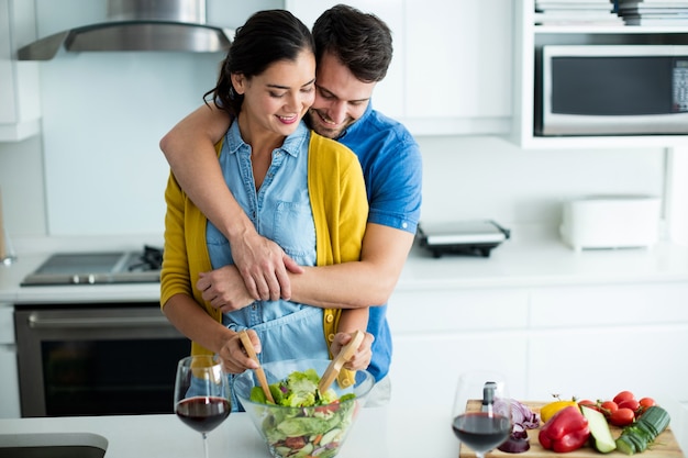 Homem abraçando mulher na cozinha de casa