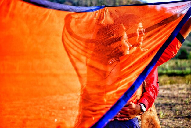 Foto homem abraçando mulher visto através de dupatta laranja