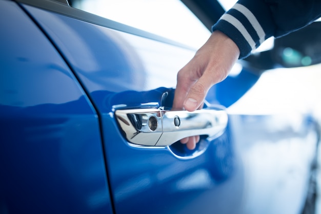 Homem abre a porta para um carro novo, inspeção de carro no showroom