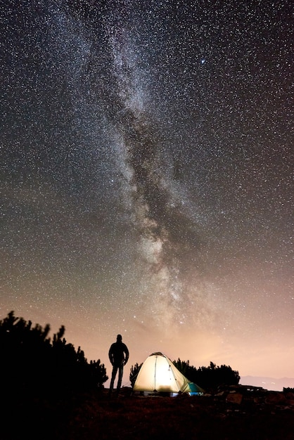 Homem acampando em uma montanha à noite