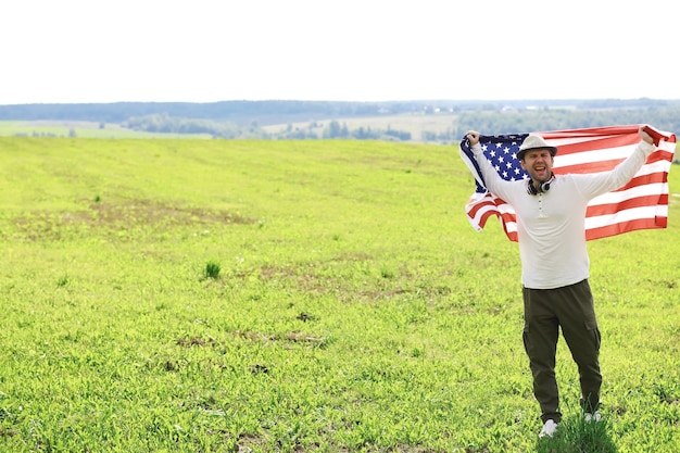 Homem acenando a bandeira americana em pé na grama fazenda campo agrícola feriados patriotismo orgulho liberdade partidos políticos imigrante