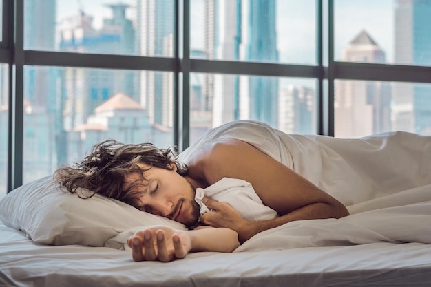 Foto homem acorda de manhã em um apartamento no centro da cidade com vista para os arranha-céus. vida no barulho do conceito de cidade grande. não dormir o suficiente