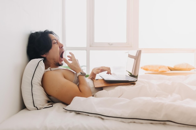 Homem acorda e trabalha com o laptop na cama logo de manhã