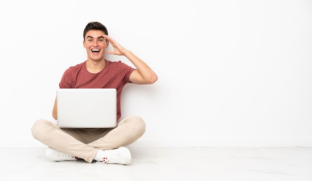 Homem adolescente sentado na flor com seu laptop