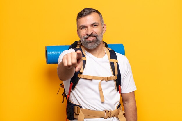 Homem adulto apontando com um sorriso satisfeito, confiante e amigável, escolhendo você