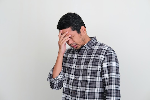 Homem adulto asiático com a cabeça para baixo mostrando expressão de estresse