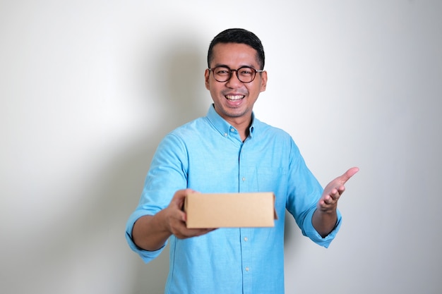 Homem adulto asiático sorrindo feliz enquanto dá uma caixa de presente