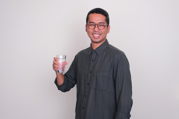 Foto homem adulto asiático sorrindo feliz enquanto segura um copo de água