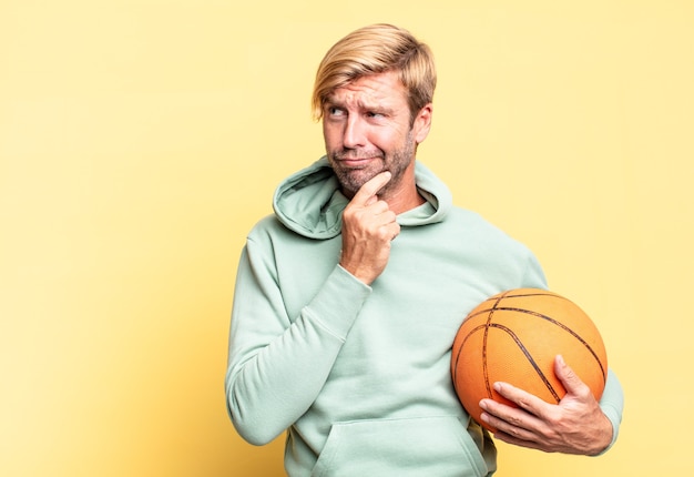 Homem adulto bonito loiro com uma bola de basquete