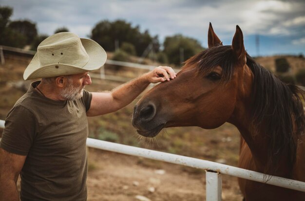 Foto homem adulto com chapéu de cowboy cavalo castanho resistente no rancho