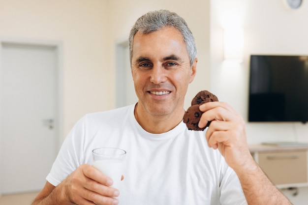 Homem adulto comendo biscoitos e bebendo leite