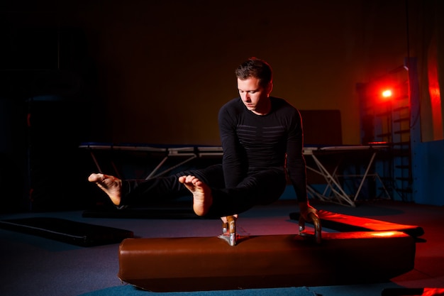 Homem adulto em roupas esportivas fazendo exercícios em aparelhos de ginástica na academia de acrobacia