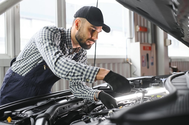 Homem adulto em uniforme de cor azul trabalha no salão do automóvel